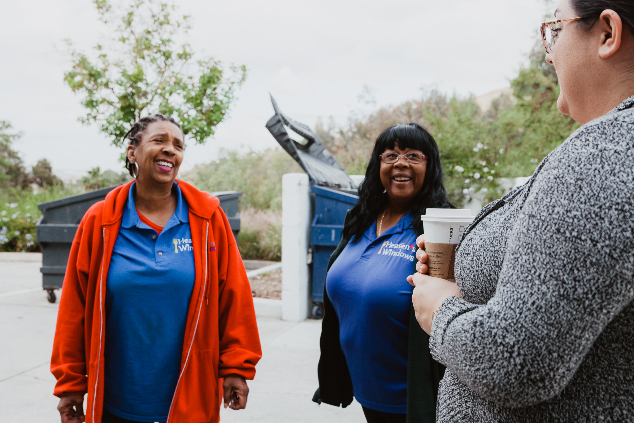 Image of 3 women, wearing Heaven's Window's blue shirt, standing and laughing