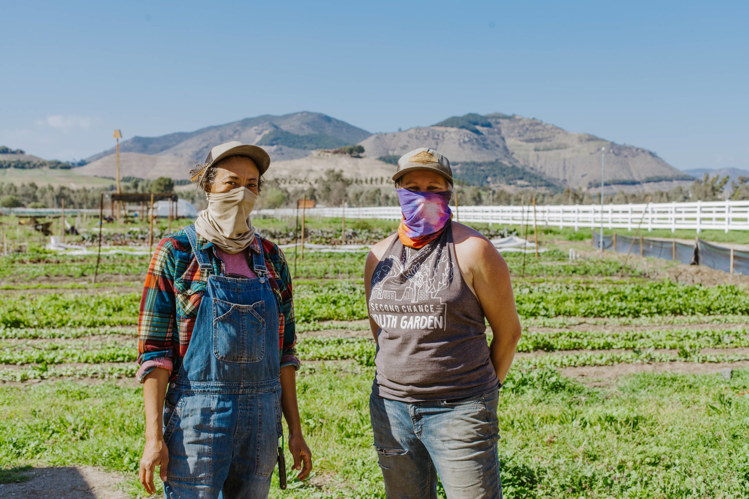 Two women standing on a farm with some hills on the background